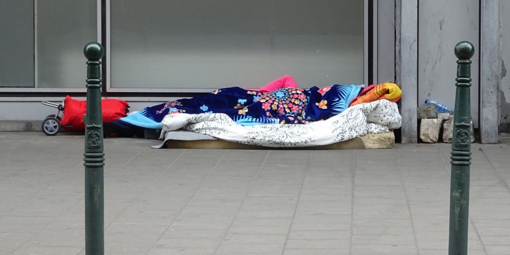 Personne sans-abri dormant sur un matelas sur le trottoir